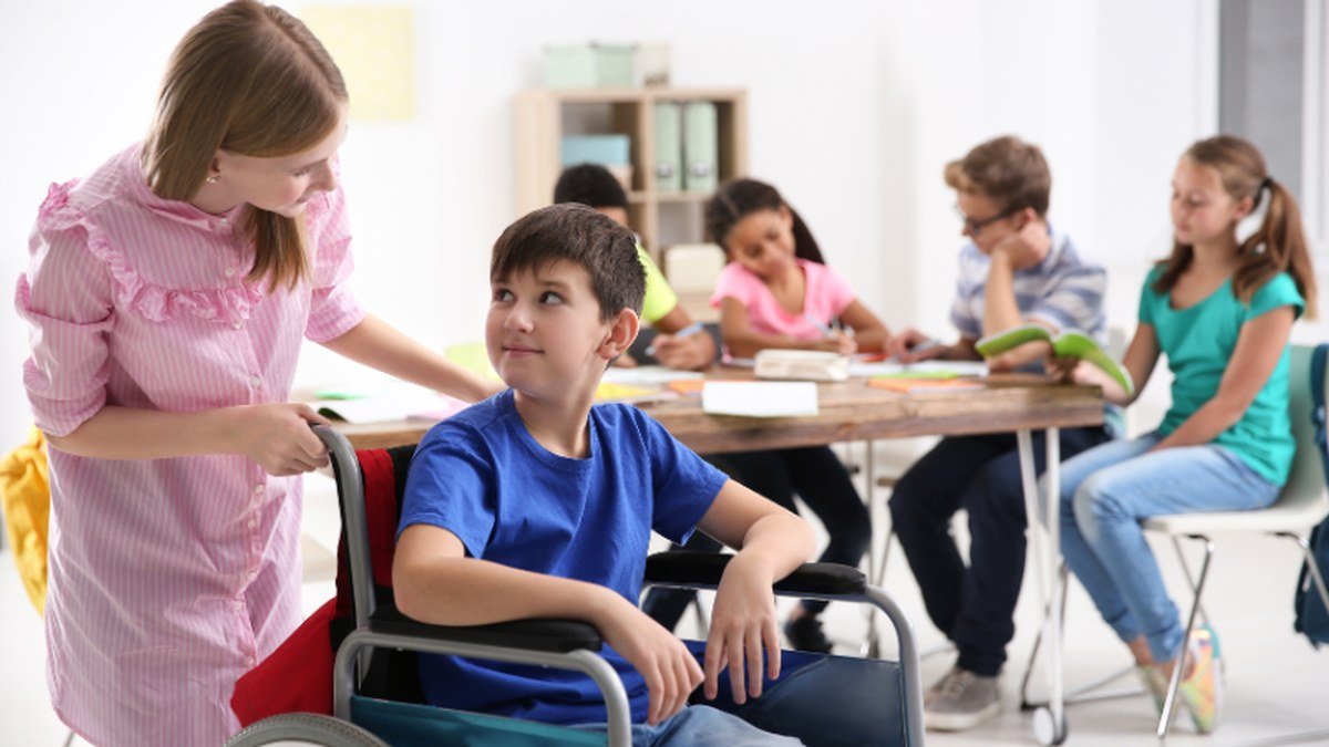 A young person being supported by a peer in a classroom setting