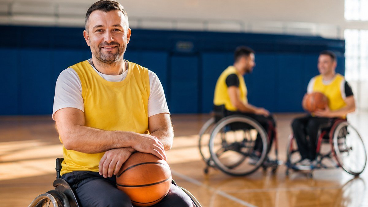 A participant taking part in wheelchair basketball with teammates