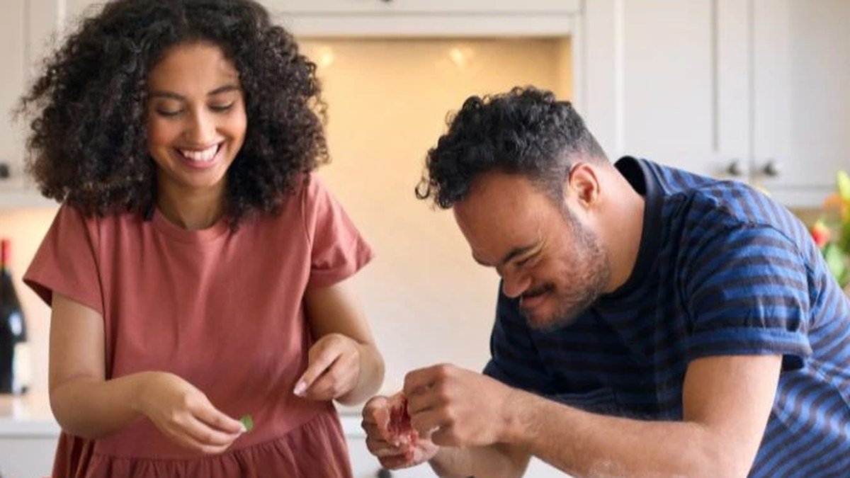 A support worker helping a participant cook in the kitchen
